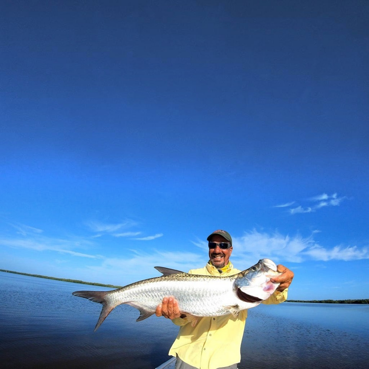 Dogfish Tackle & Marine angler holding a large silver tarpon caught on a Yo-Zuri Crystal Minnow lure in open water.