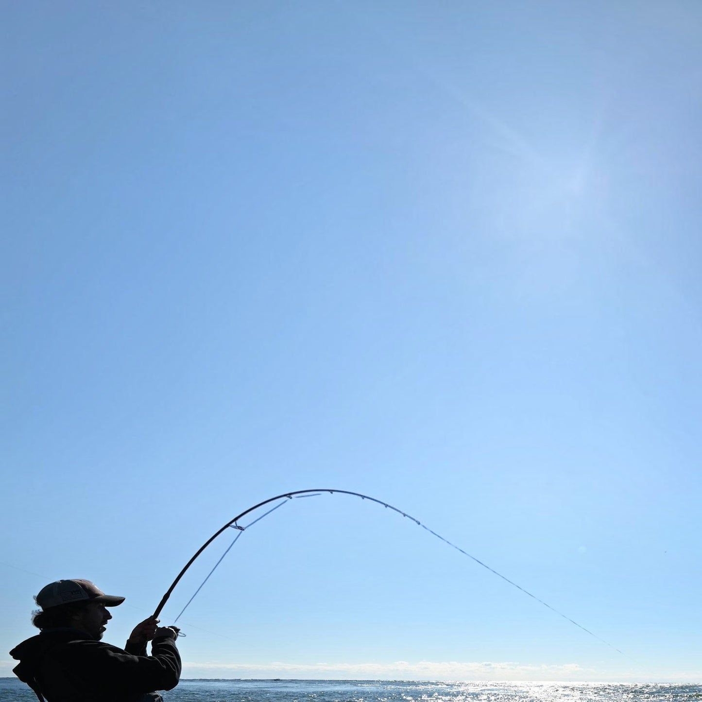 Dogfish Tackle & Marine angler using Seaguar Gold Label fluorocarbon leader on a fishing rod against a clear blue sky