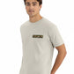 Man wearing a beige t-shirt with a logo on a white background