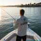 Man fishing on a boat by a body of water during sunset.