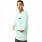Person wearing a light green long-sleeve shirt with a brand logo on a white background