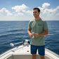 Man on a boat holding a can, with ocean and sky in the background