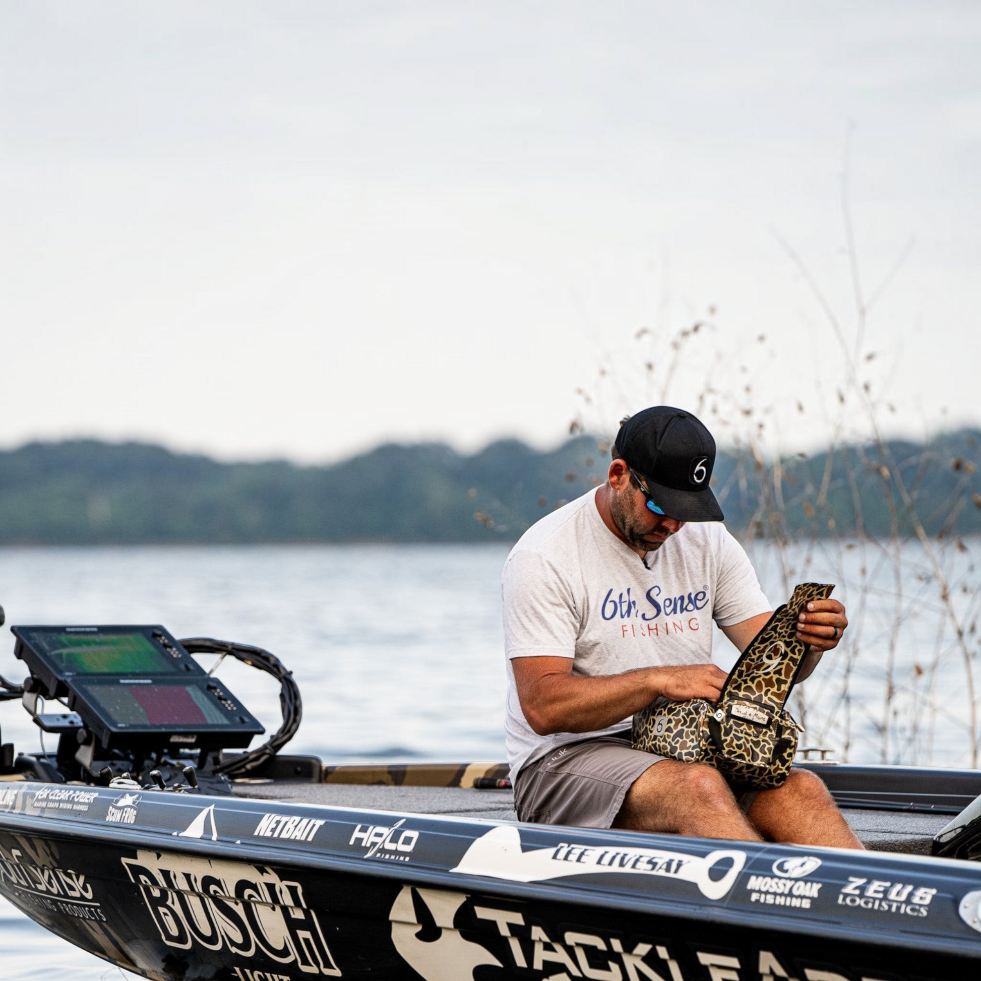 Angler on a Dogfish Tackle & Marine boat opening a camo 6th Sense Large Bait Bag to organize soft plastic lures.