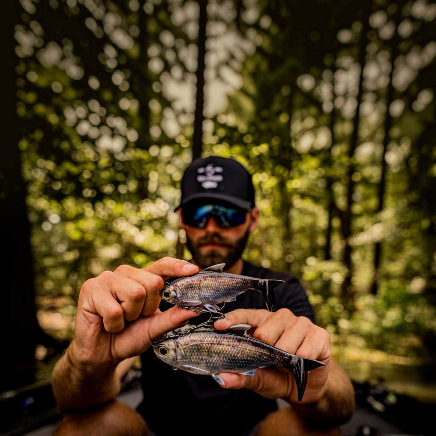 Dogfish Tackle & Marine angler holding two 6th Sense The Option swimbaits with realistic scales and dorsal fins