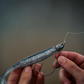 Dogfish Tackle & Marine 6th Sense Axle swimbait jig head with a silver glitter soft plastic lure held in hand