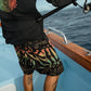Dogfish Tackle & Marine black boardshorts with abstract colorful print, zip pockets, and 19in outseam.