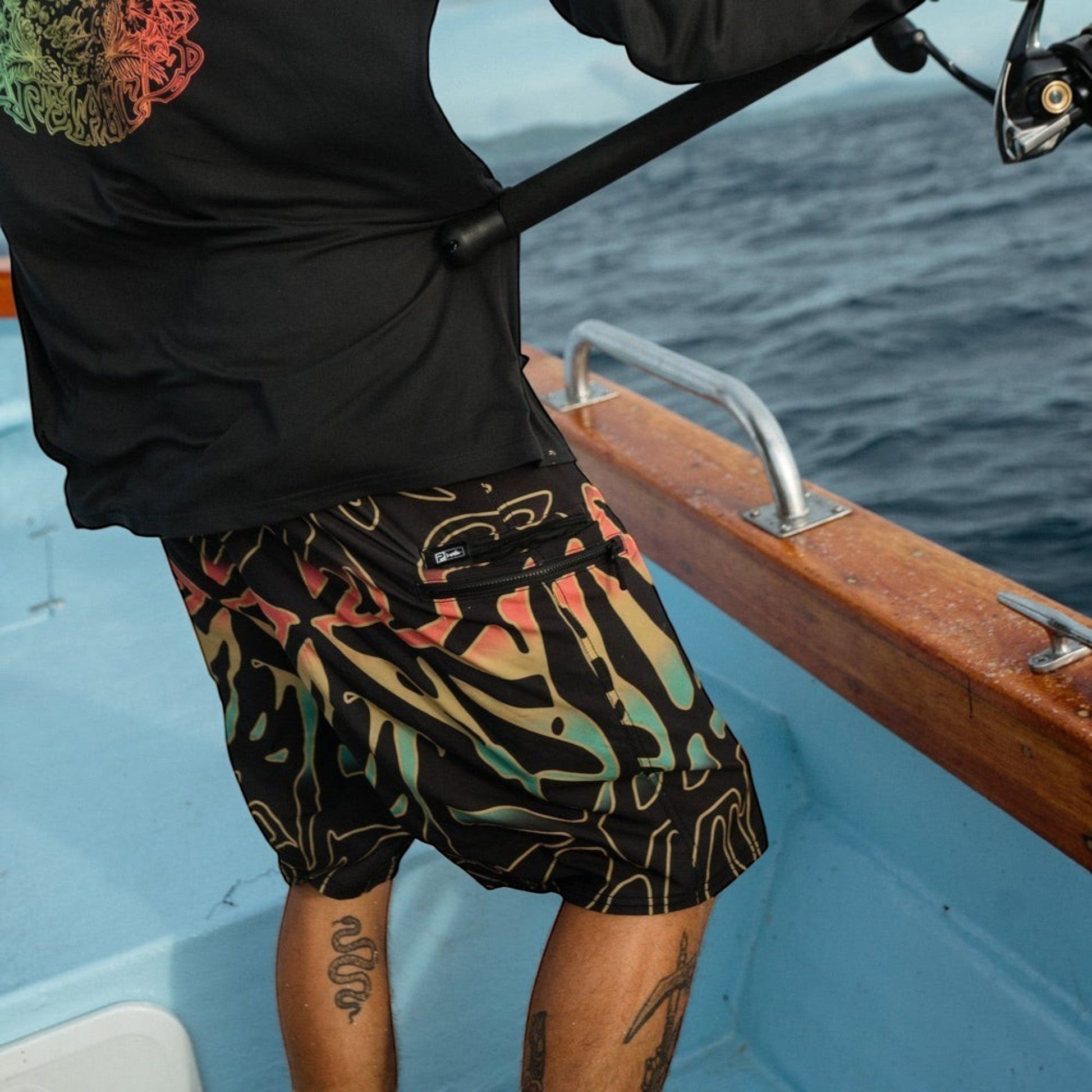 Dogfish Tackle & Marine black boardshorts with abstract colorful print, zip pockets, and 19in outseam.