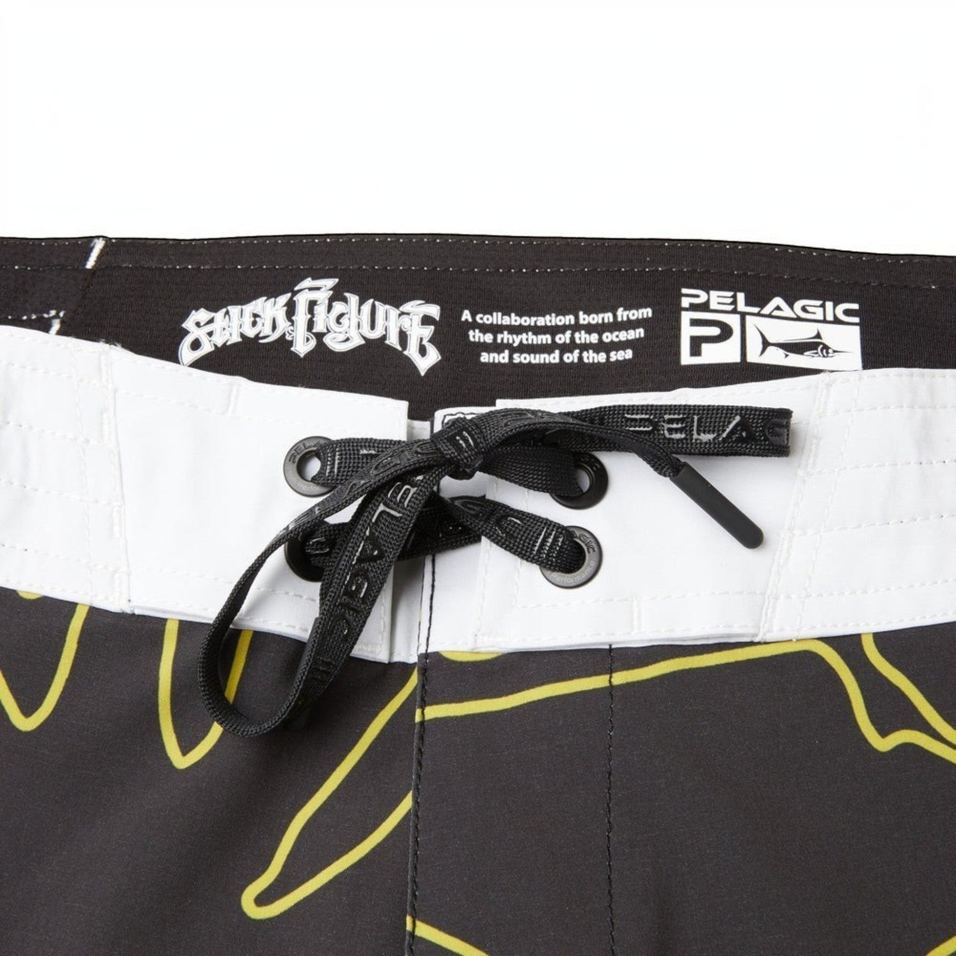 Dogfish Tackle & Marine black boardshorts with yellow abstract design, white waistband, and black drawstring.