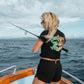 Dogfish Tackle & Marine women's black cropped tee with colorful "Stick Figure" graphic on back, 60% organic cotton.