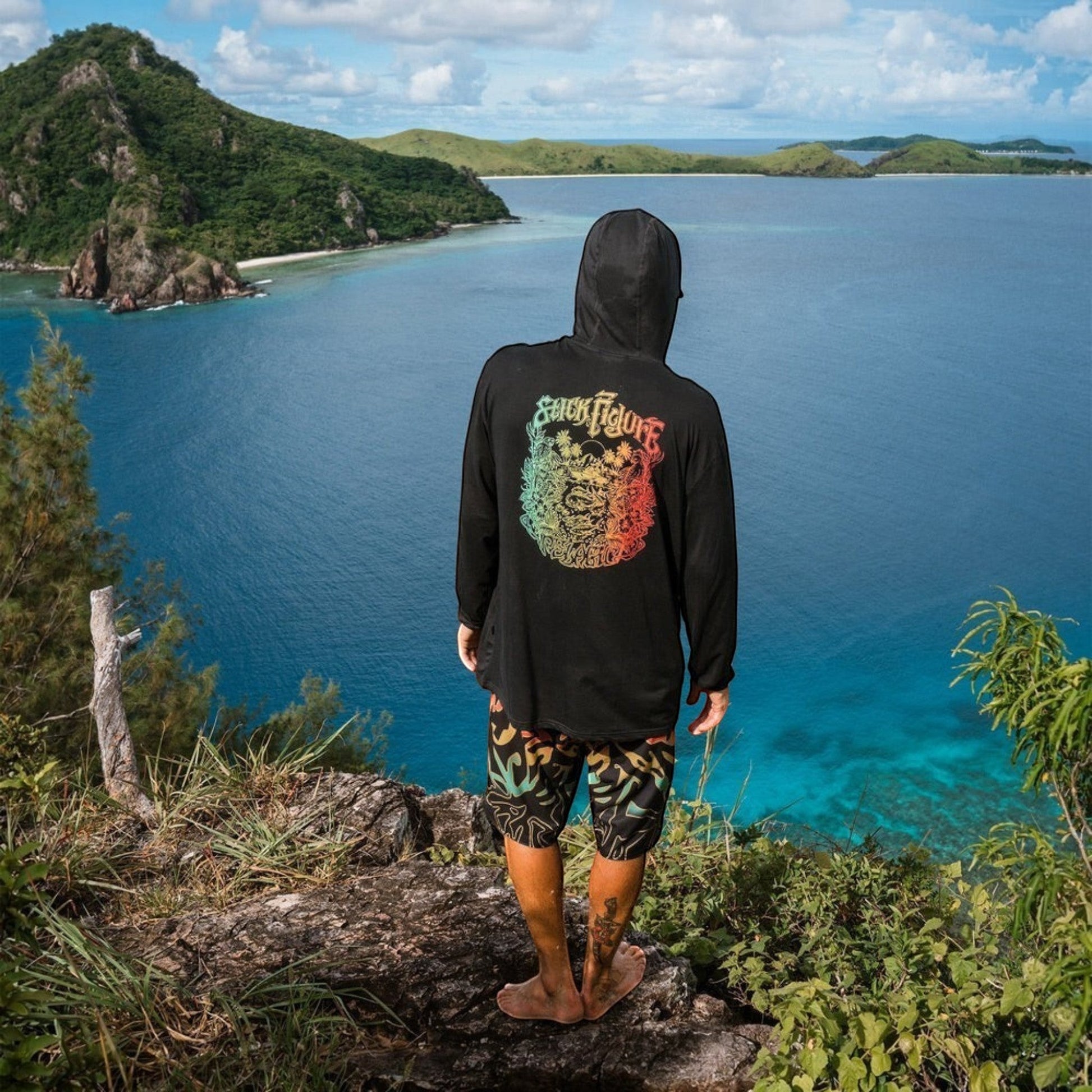 Dogfish Tackle & Marine black long-sleeve rashguard with colorful graphic on back, paired with patterned boardshorts.