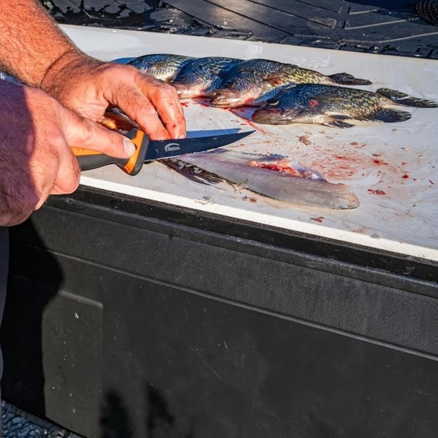 Dogfish Tackle & Marine Danco Lunar-I 6in folding fillet knife with orange and black grip filleting fish on a board