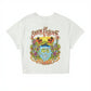 Dogfish Tackle & Marine white cropped t-shirt with a colorful graphic of a tropical scene, parrots, fish, and palm trees. Made of 60% organic cotton and 40% recycled polyester.