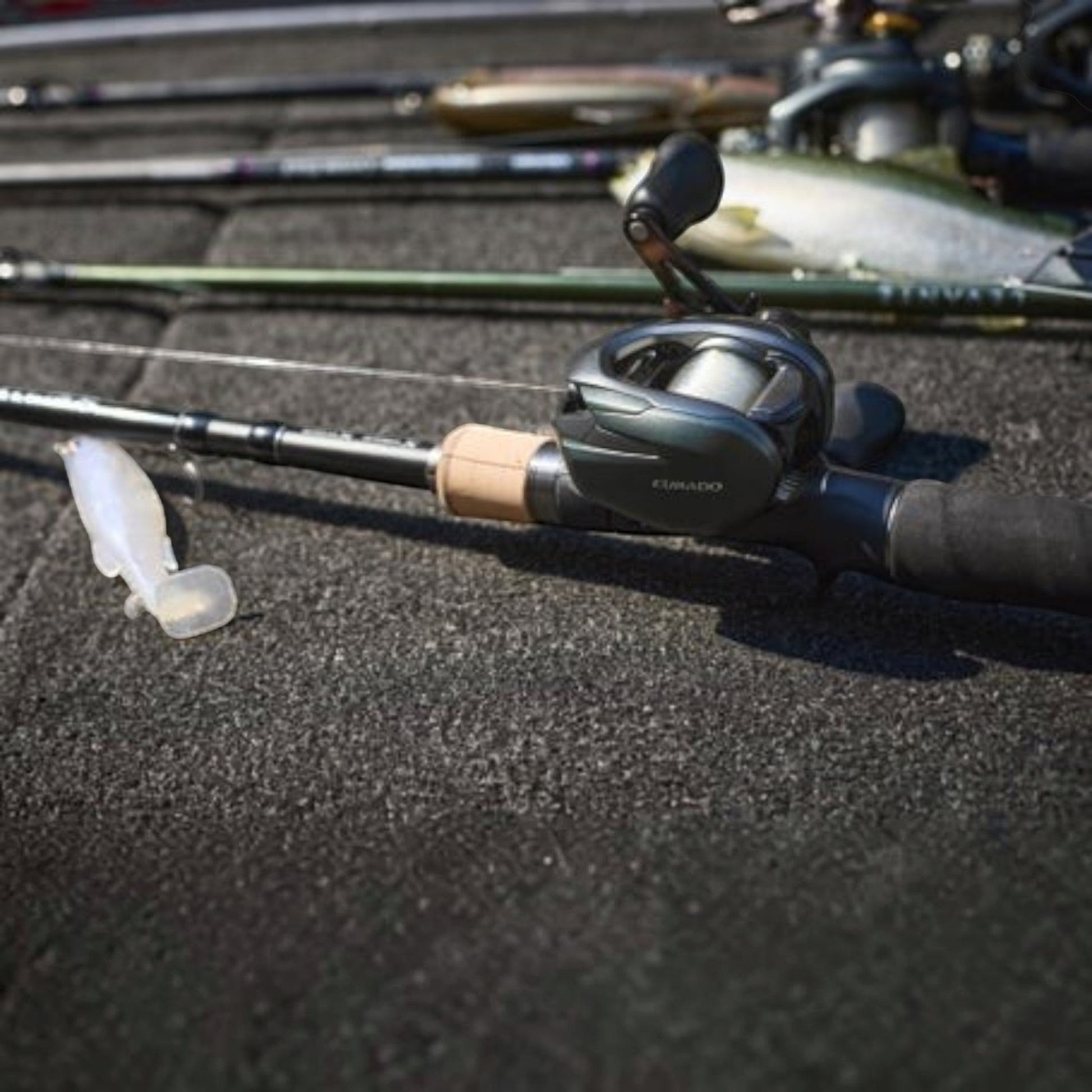 Dogfish Tackle & Marine Shimano Curado 150 M baitcasting reel in dark green with a tan cork handle grip and a soft plastic lure.