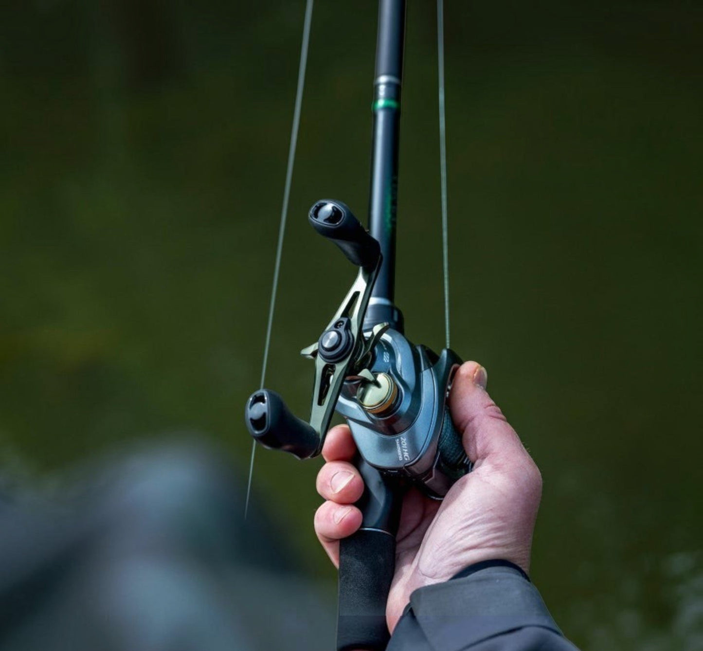 Dogfish Tackle & Marine Shimano Curado DC baitcasting reel in gunmetal grey with gold accents, held by a hand.