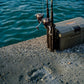 Dogfish Tackle & Marine Shimano Nexave FJ spinning reels with fishing rods and tackle box on a concrete pier by the water.