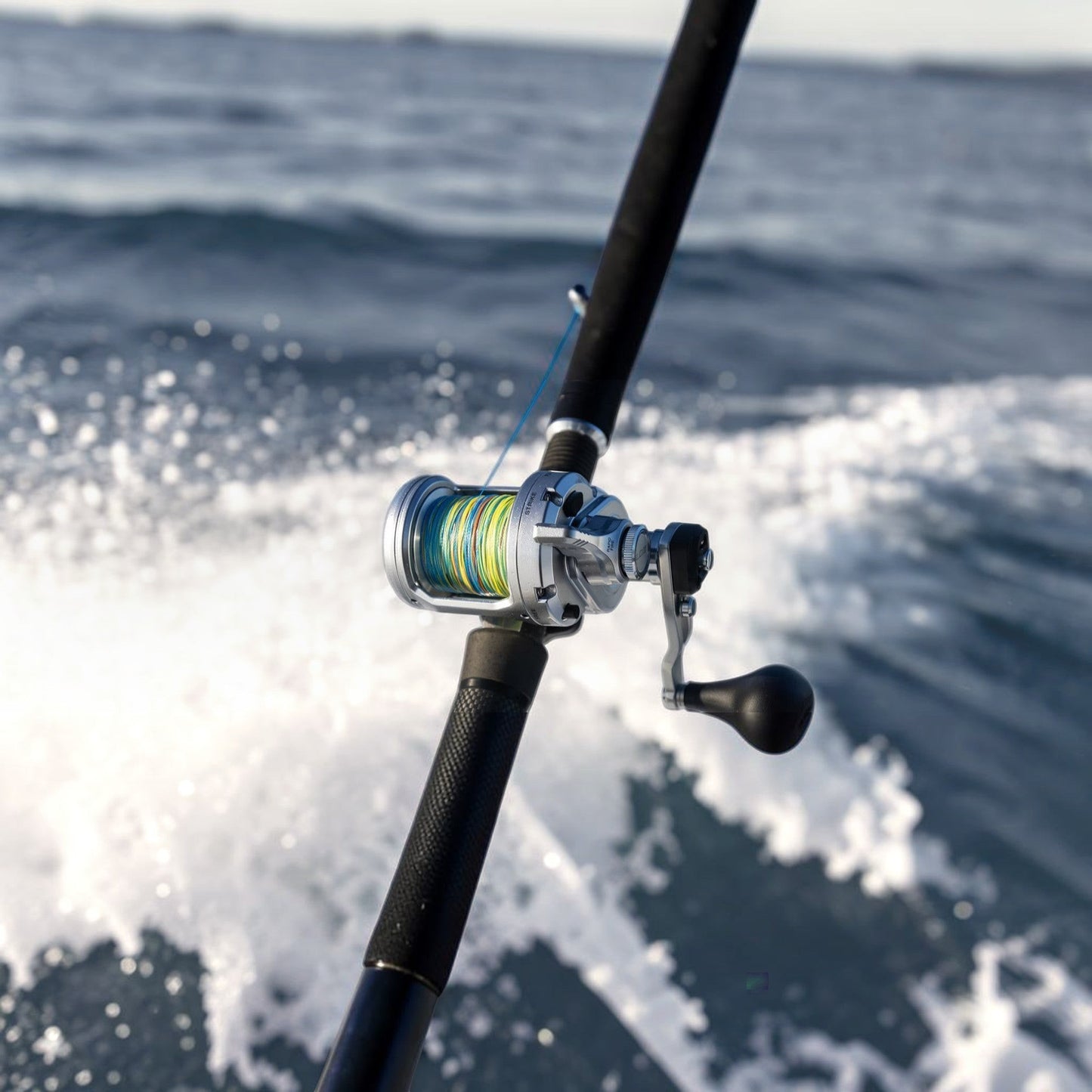 Dogfish Tackle & Marine Shimano Speedmaster II conventional fishing reel with multi-colored line on a fishing rod over choppy water.