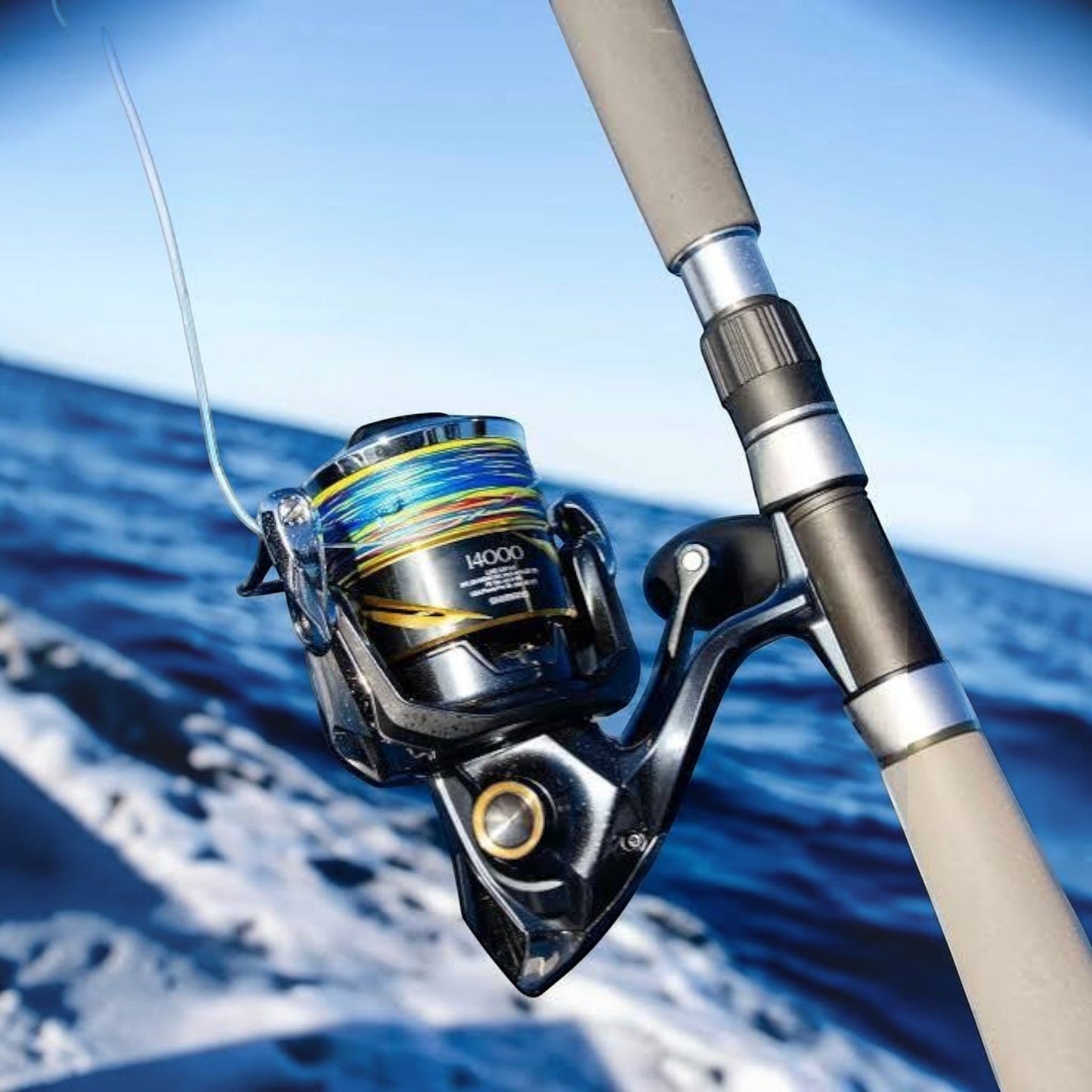 Dogfish Tackle & Marine Shimano 2025 Stella SW D 14000 spinning reel with multi-colored braided line on a fishing rod over blue water.