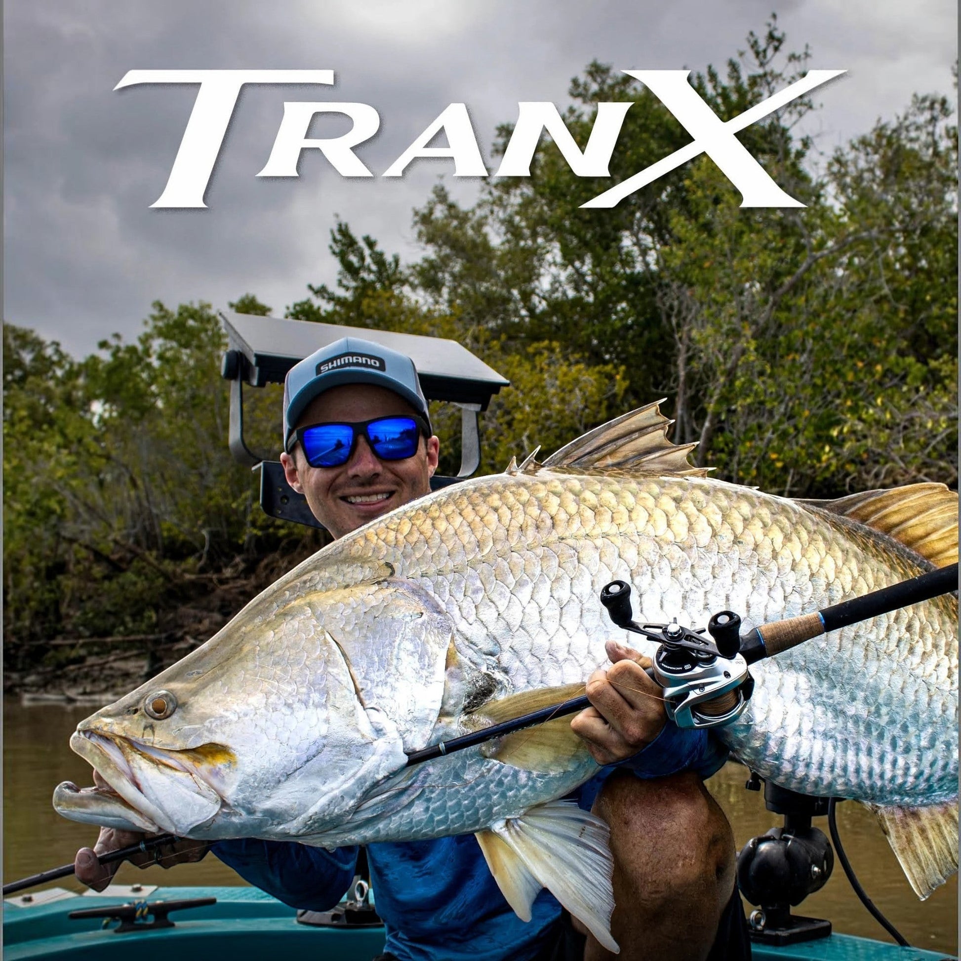 Dogfish Tackle & Marine: Man holding a large silver fish with a Shimano Tranx B baitcasting reel and rod.