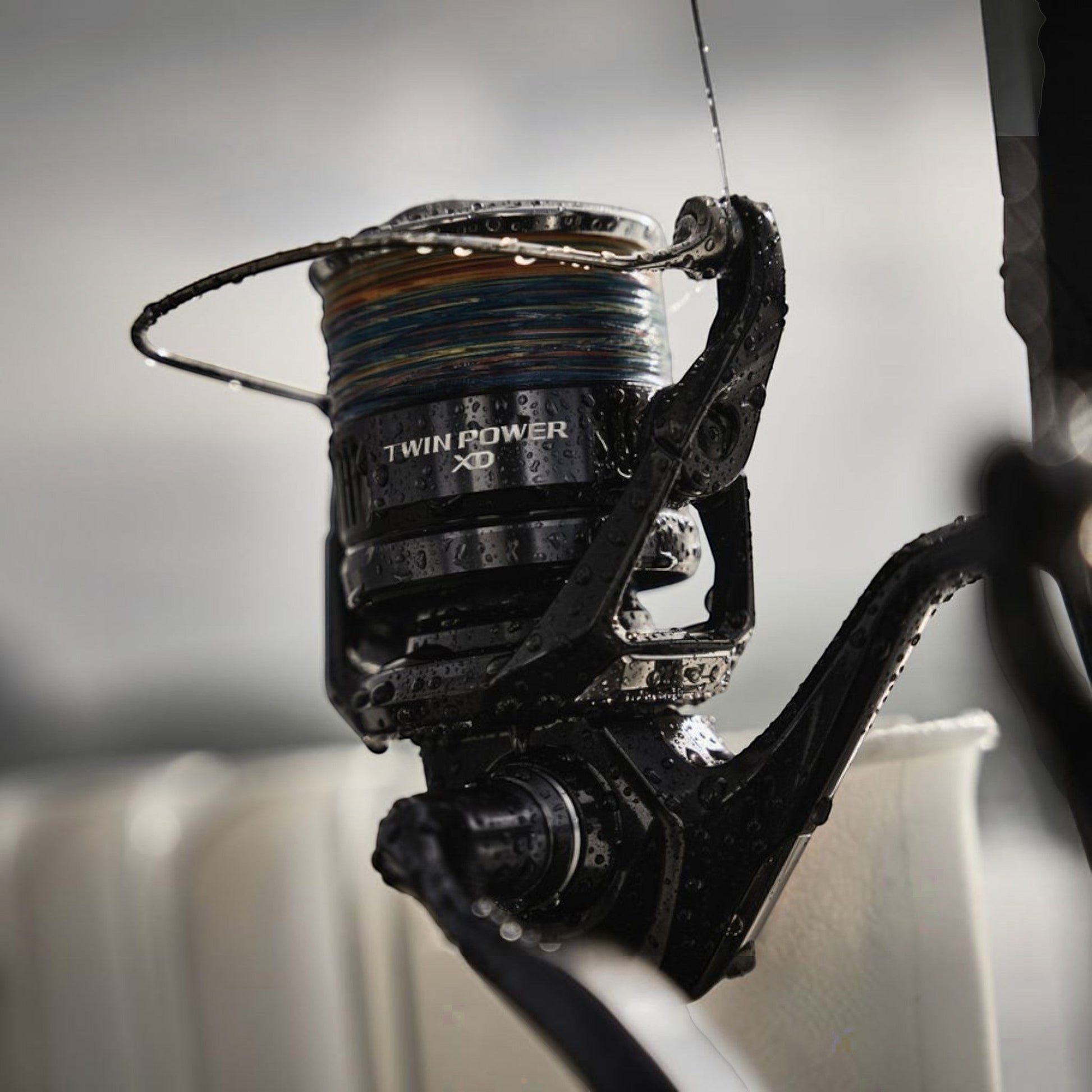Dogfish Tackle & Marine Shimano Twin Power XD FB spinning reel, black, with multi-colored fishing line and water droplets.