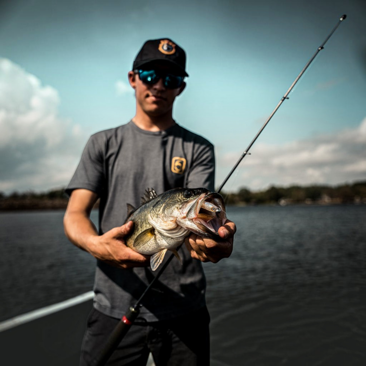 Dogfish Tackle & Marine angler holding a largemouth bass with a 6th Sense Strobe Minnow lure in its mouth on a lake