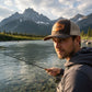 Dogfish Tackle & Marine brown trucker hat with tarpon patch and mesh back, worn by a man fly fishing.