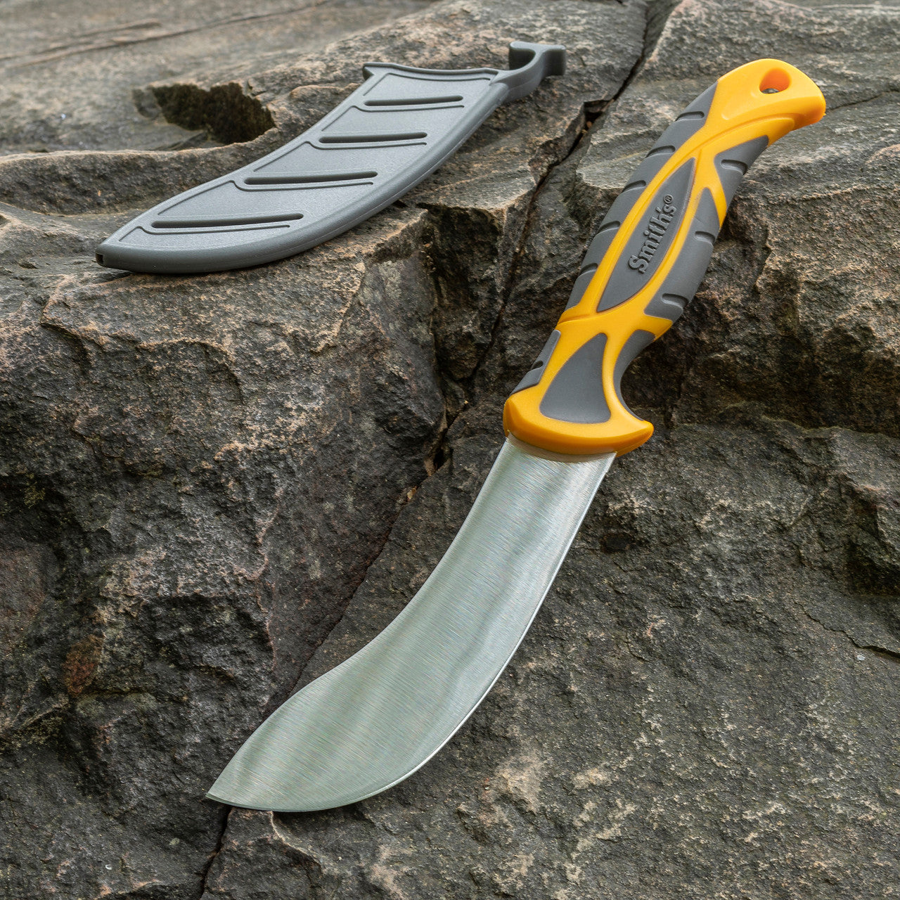Bowie knife with a gray blade and orange handle on a rocky surface