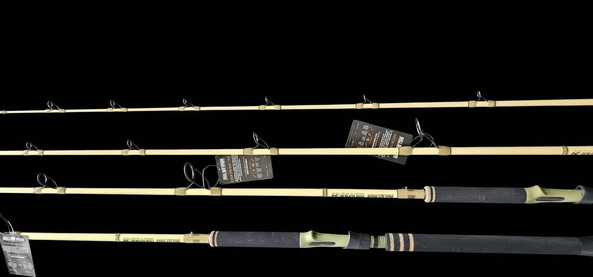 Four fishing rods displayed horizontally against a solid black background, showing both the blank and the wrapped handle sections with tags attached.
